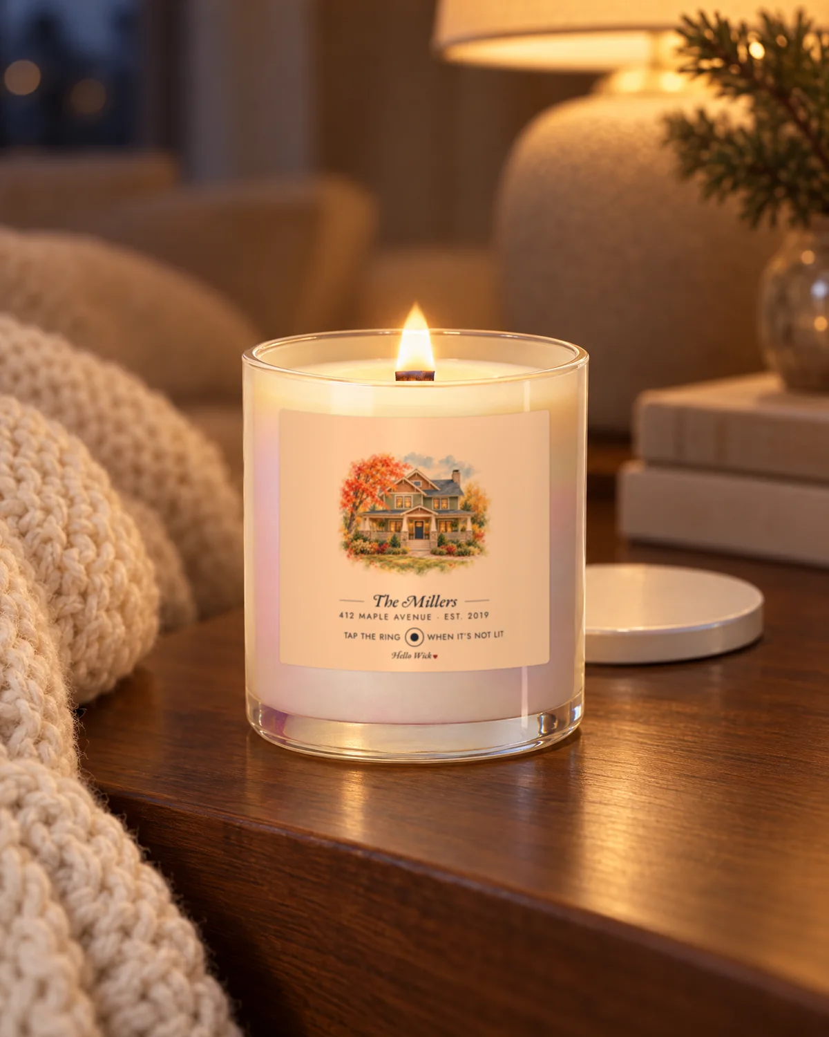 Placeholder photo: a lit Hello Wick candle labeled The Millers on a side table by a lamp