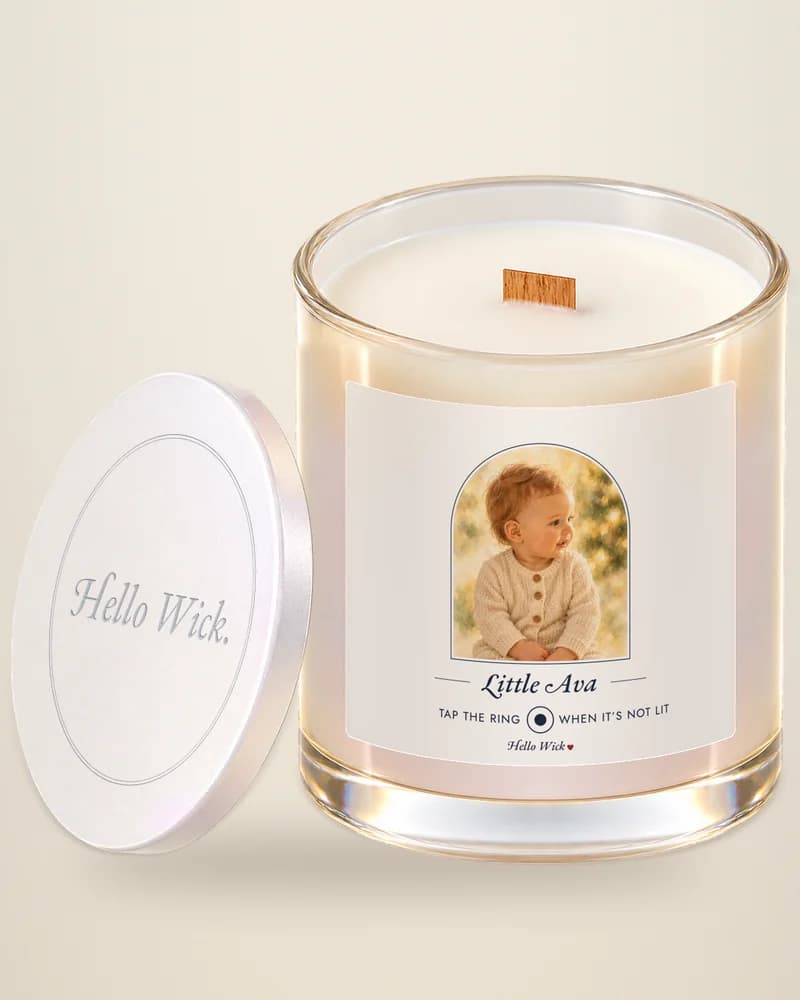 A Hello Wick candle labeled Little Ava, with a watercolor of the baby, its lid beside it