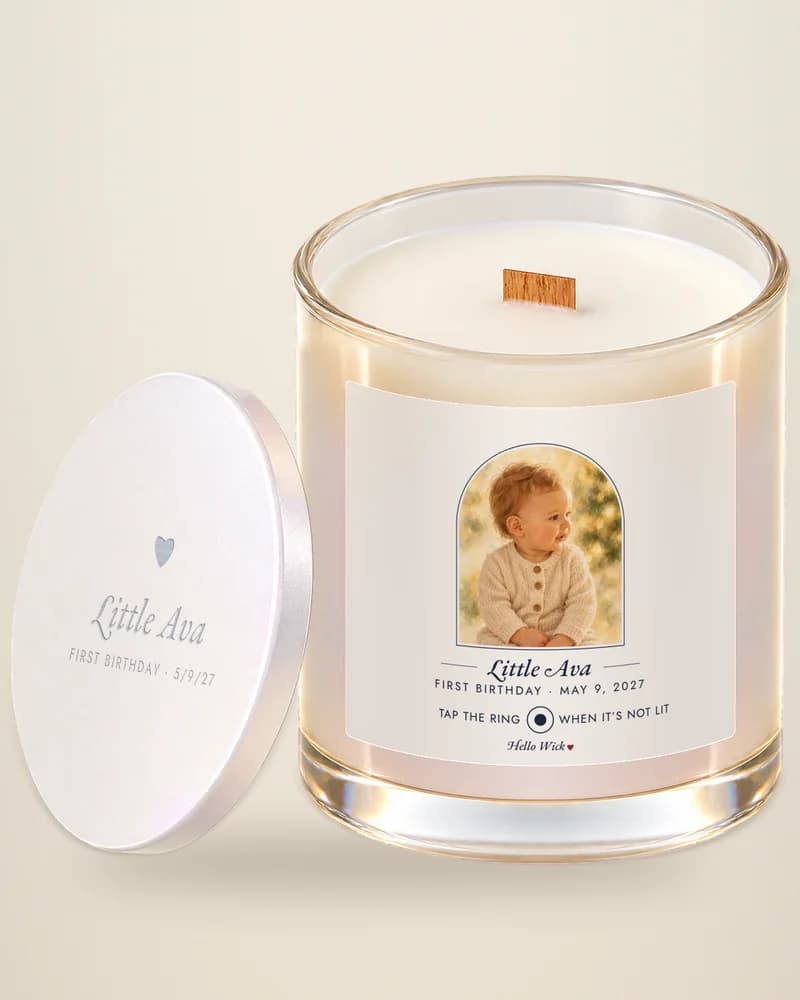 A Hello Wick candle labeled Little Ava, first birthday, with the baby in the arch